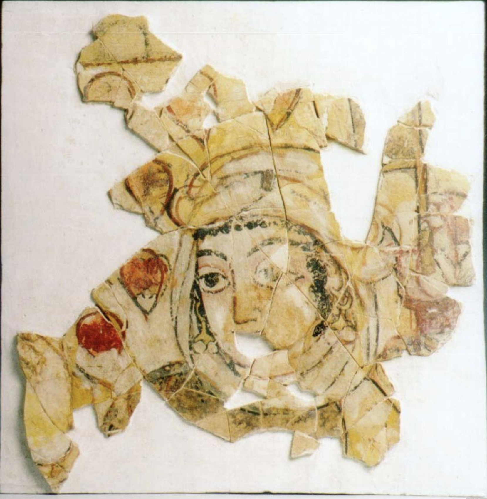 A fragment of Umayyad mural painting showing the face of a woman, her features and eyes painted in full